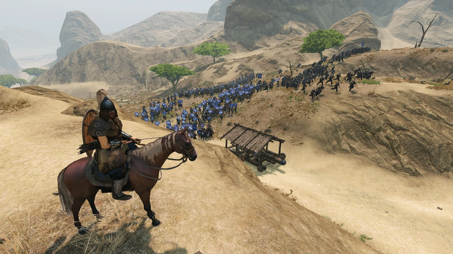 A mounted commander overlooks a blue-shielded army advancing through a desert valley
